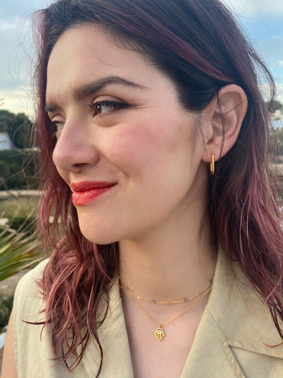 Model wearing gold plated sterling silver hamsa hand necklace with aquamarine semi-precious stone and labradorite beaded choker
