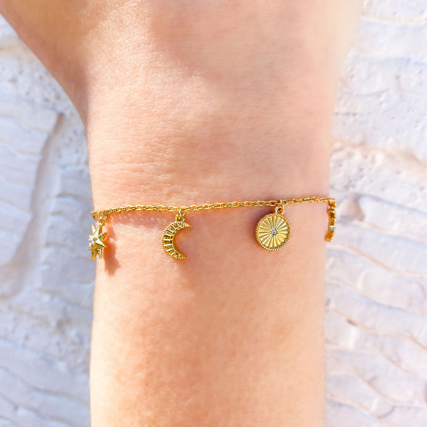 Model wearing gold plated sterling Silver moon and star charm bracelet with CZ crystals