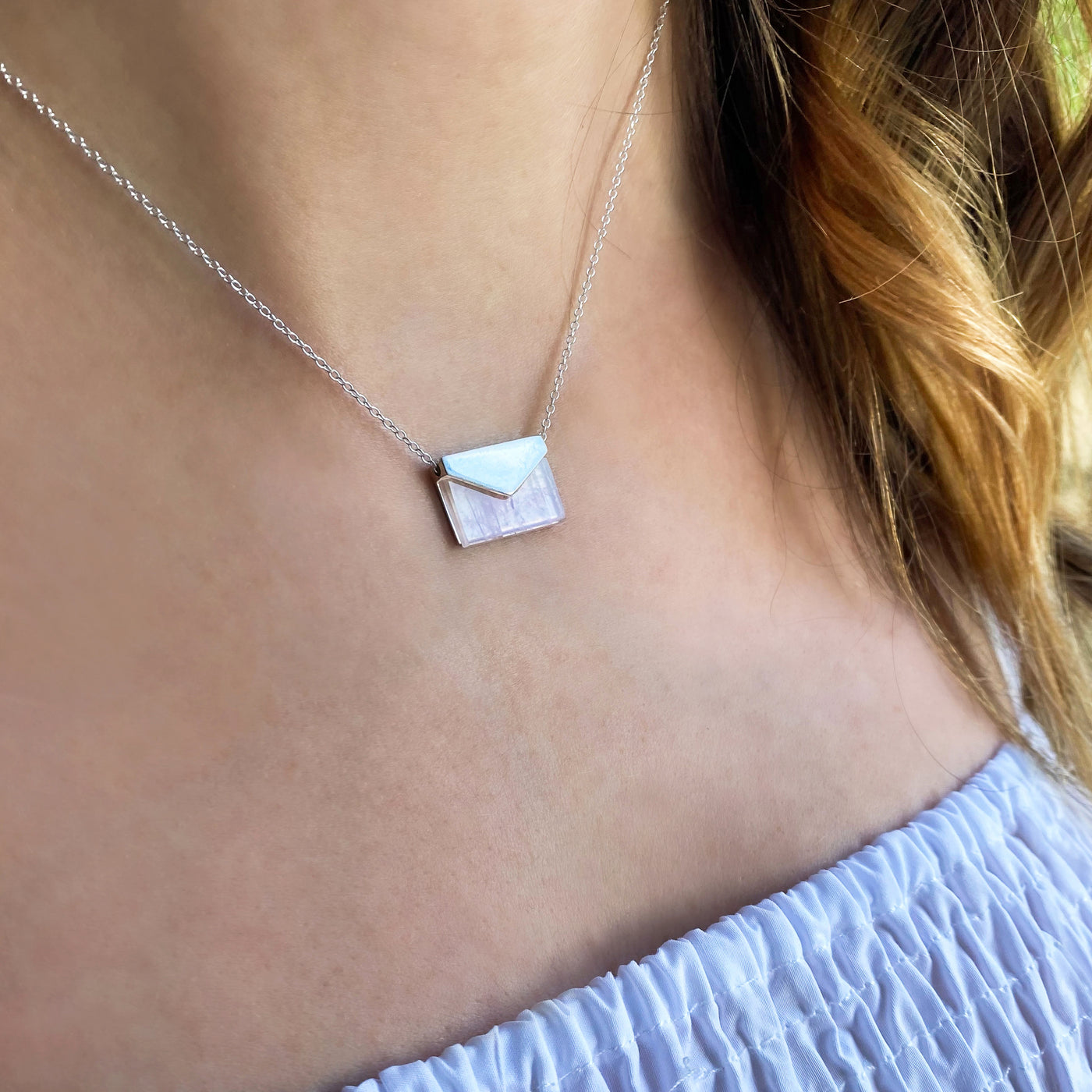Model wearing silver envelope necklace with rose quartz