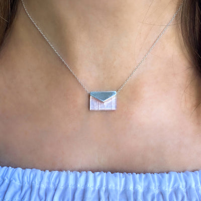 Model wearing silver envelope necklace with rose quartz