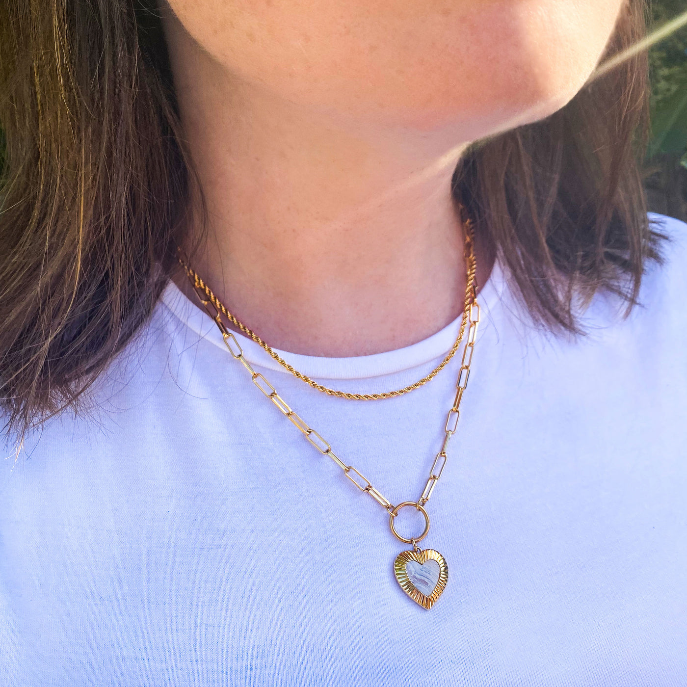 Model wearing simple gold twist chain necklace and chunky chain with blue lace agate heart charm