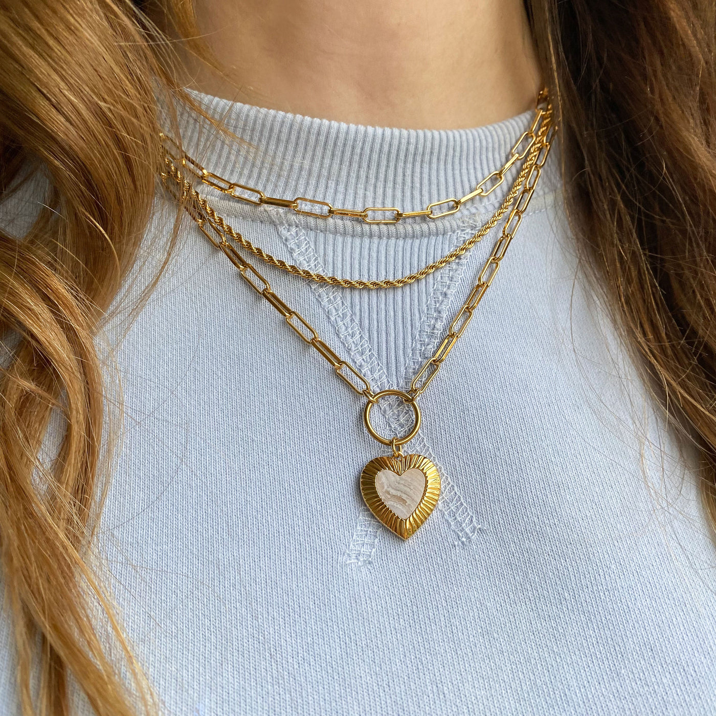 Model wearing simple gold twist chain necklace, plain chunky chain necklace and blue lace agate heart necklace